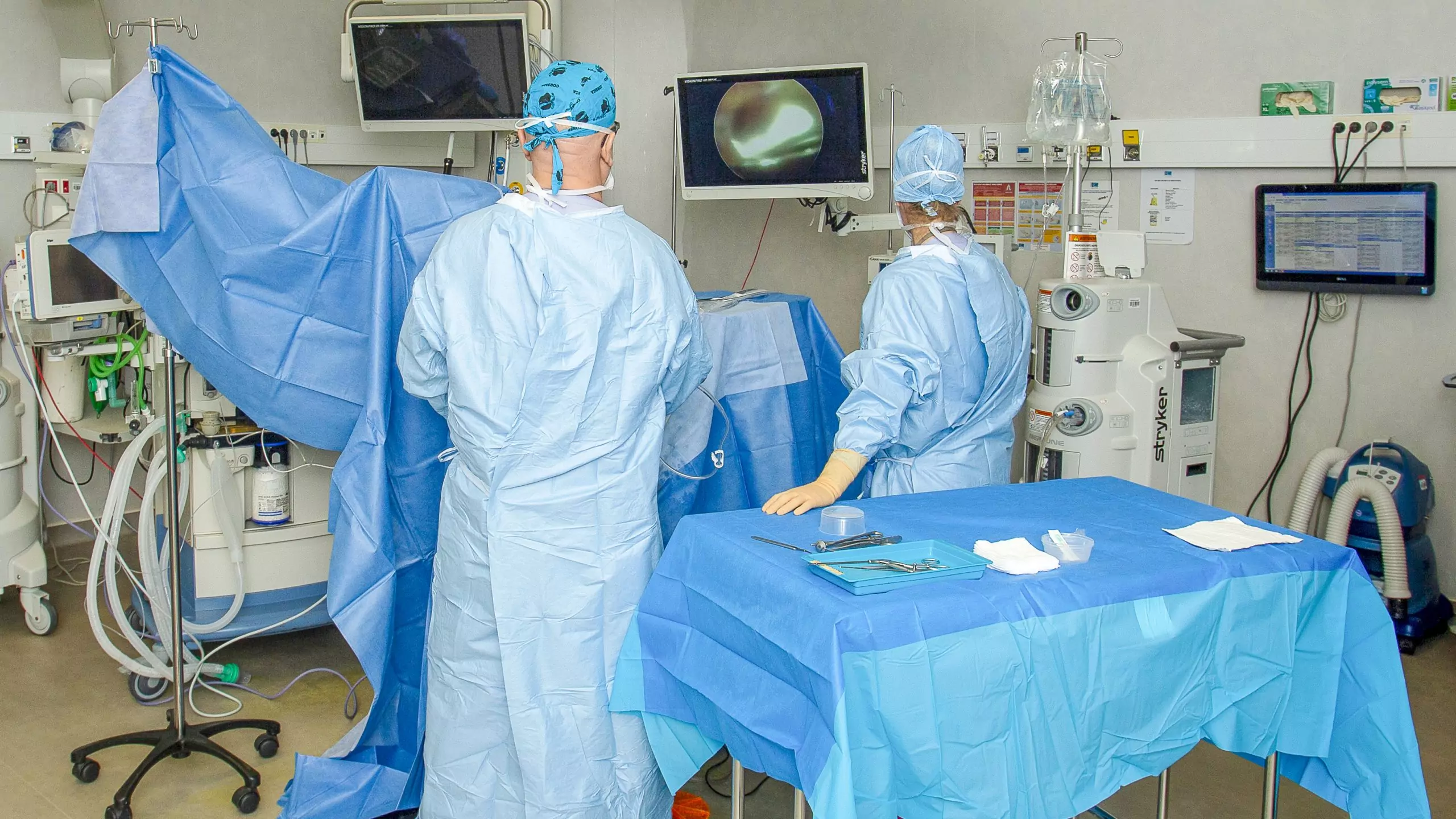 Chirurgiens en tenue stérile opérant dans un bloc moderne avec assistance vidéo endoscopique.